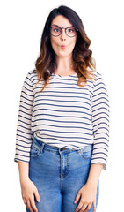 Fototapeta premium Beautiful young brunette woman wearing casual clothes and glasses making fish face with lips, crazy and comical gesture. funny expression.