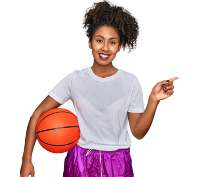 Young african american girl playing baseball holding bat and ball smiling happy pointing with hand and finger to the side