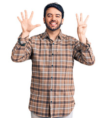 Young hispanic man wearing casual clothes showing and pointing up with fingers number eight while smiling confident and happy.