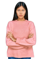 Beautiful young asian woman wearing casual winter sweater skeptic and nervous, disapproving expression on face with crossed arms. negative person.