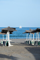 Straw beach umbrellas and comfortable sun loungers on Maditerranean's shore.