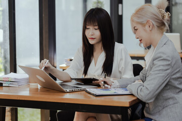 Happy smiling business woman Working on laptop computer with paperwork at desk in a modern office,  business finance technology concept.
