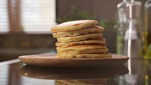 Stack of delicious pancakes drops in wooden plate. Stack of american style fluffy buttermilk pancakes for sweet breakfast. High quality 4k footage