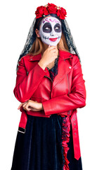 Obraz premium Woman wearing day of the dead costume over background with hand on chin thinking about question, pensive expression. smiling with thoughtful face. doubt concept.