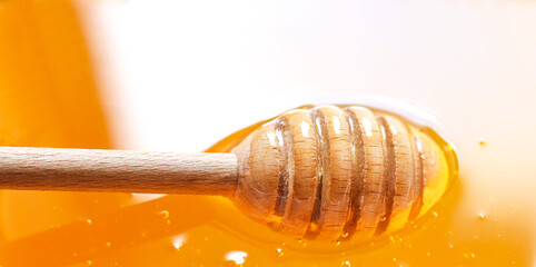 Texture of natural golden honey with air bubbles as a background. Wooden honey dipper ( spoon ). Free space for text.