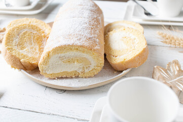 Swiss roll with whipped cream filling on a white coffee table