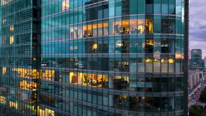 flying around a modern glass skyscraper at night with illuminated office windows, modern business centre building in the evening. Corporate business. Light in building windows, urban lights