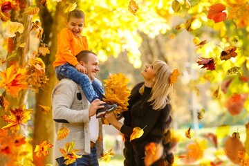 Naklejka na ściany i meble Family playing in autumn park having fun
