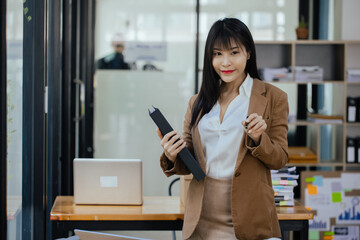 Asian businesswoman working  with calculator and laptop computer at office workplace. business planning, investment and marketing on table in office.

