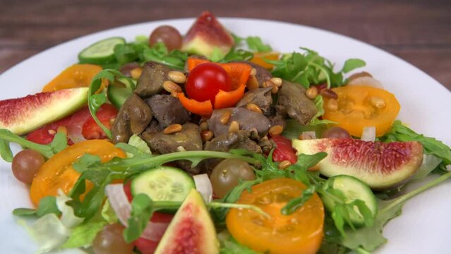 Recipe for fried chicken liver and gizzards with salad and tomatoes, cucumber, figs, grapes on a white plate, High quality video