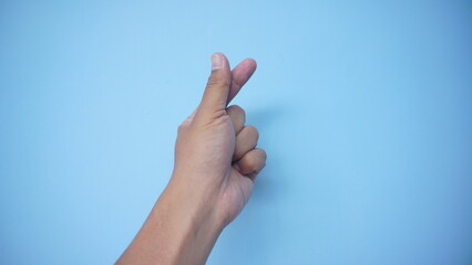 A hand signs gesture to be little heart from tip of thumb and index finger on blue background