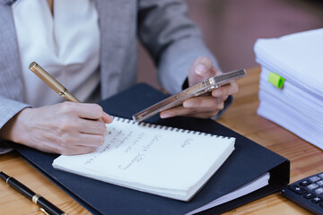 Close up of businesswoman hands using smart phone at workplace in office.