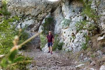 Young man in cap walking hiking route in steep mountains