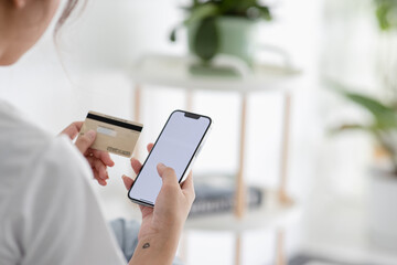 A close-up photo of a young woman using her smartphone and her credit card at home. Online shopping ( credit card mockup )