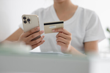 Close-up of Asian woman with smartphone and bank card Participate in online shopping through mobile at home. Female shopper is happy with online shopping.