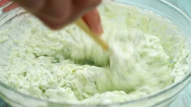 The chef stirs the greek tzatziki salad.
