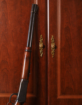 Classic Lever-action Rifle Leaning Against Ornate Dresser Cabinet Door