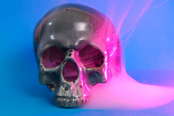 Human skull in pink and blue smoke on a blue background. Halloween concept