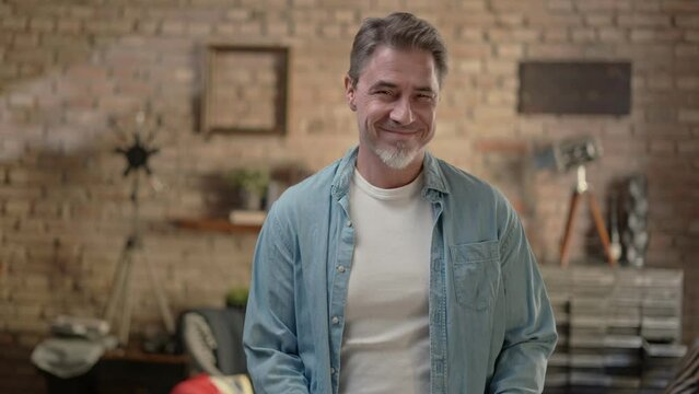 Middle aged casual man at home. Portrait of mid adult, mature age man, happy smiling. Industrial loft apartment, copy space.