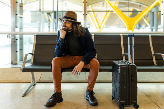 Trendy Male Traveler Sitting On Chair In Airport