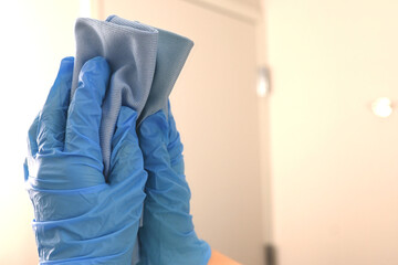 Gloved hand cleaning a mirror in a hotel bathroom. Housekeeper using a microfiber cloth to clean a mirror. Custodian wearing gloves
