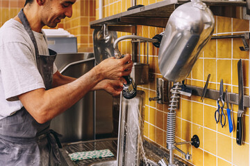 Crop male cook washing baking pan