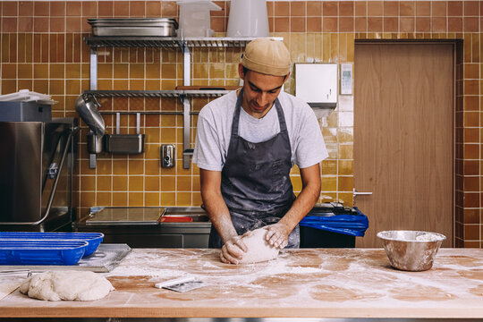 Man cook shaping dough in bakery