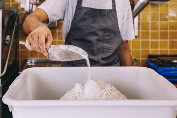 Baker adding ingredients for dough