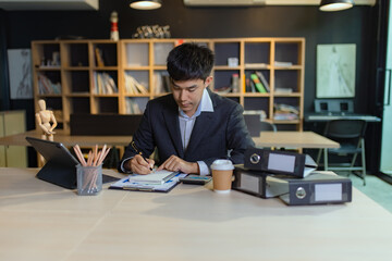Fototapeta na wymiar Asian Happy businessman working on smartphone with accounting documents at the table in office. Happy man working concept.