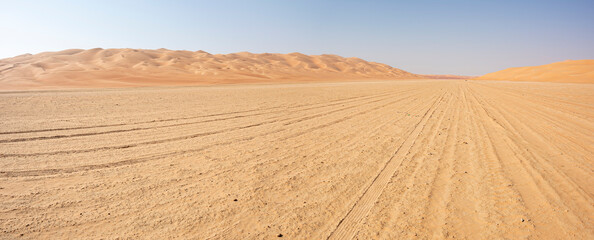 Fototapeta na wymiar Panoramic view of a Track in the desert with blue sky and copy space