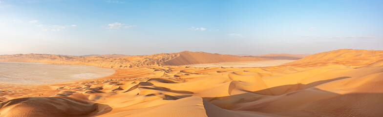 Panoramic and scenic view of dunes of the Emprty Quarter with blue sky, Middle East. Horizontal with copy space