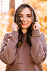 Young woman in sweater in autumn park. Sunny weather. Fall season.