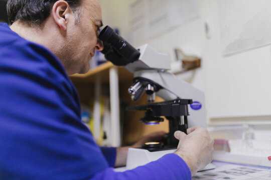 Doctor looking through microscope in laboratory