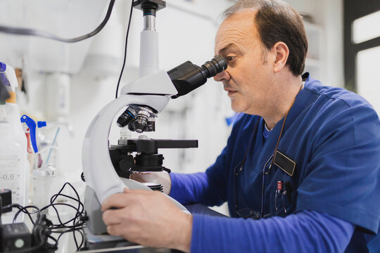Doctor looking through microscope in laboratory
