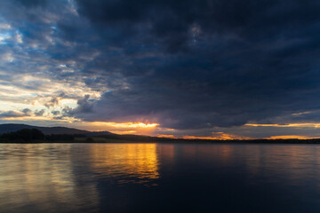 Fototapeta na wymiar Majestic sunset dramatic sky above pond and distant hil. Czech landscape, long exposure