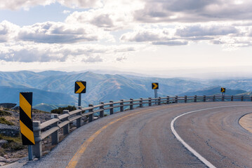Empty road against ridge under shiny cloudy sky