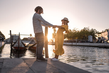 Smiling couple holding hands against river on city embankment