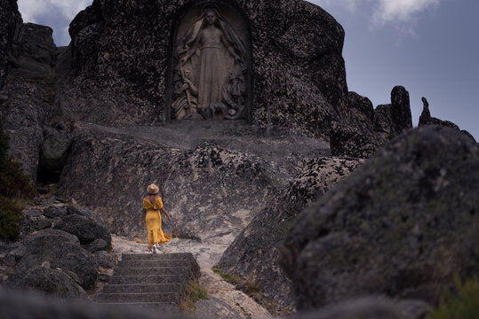 Unrecognizable tourist admiring sculpture of Virgin in mountains