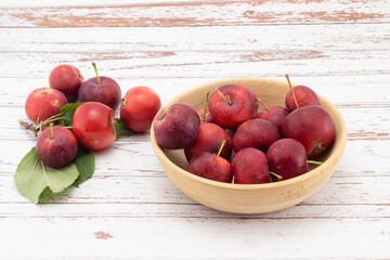 Fresh small apples in wooden bowl on white wooden table. Wild red crabapples in bowl