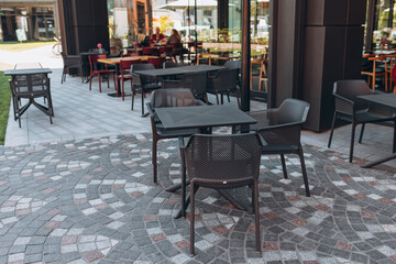 Empty modern chairs in outdoor cafe or restaurant on summer day. Reastaurant tables waiting for customers
