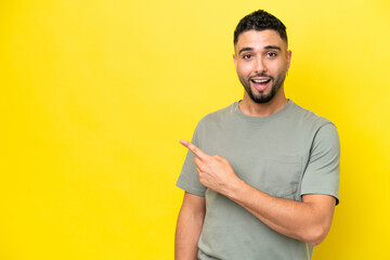 Young Arab handsome man isolated on yellow background surprised and pointing side