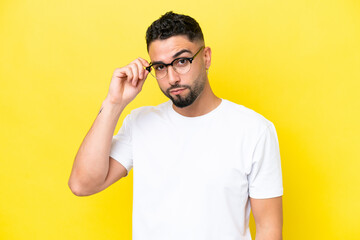 Fototapeta premium Young Arab handsome man isolated on yellow background With glasses and frustrated expression