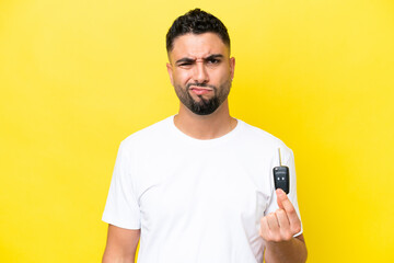 Young Arab man holding car keys isolated on yellow background with sad expression