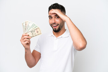 Young Arab man taking a lot of money isolated on white background doing surprise gesture while looking to the side