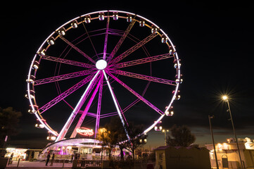 Italy, September 2022: view of the ferris wheel of Rimini with all the colored lights near the beach of the Riviera Romagnola