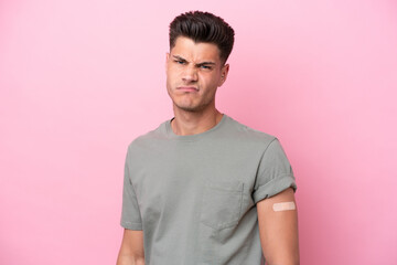 Young caucasian man wearing band-aids isolated on pink background with sad expression