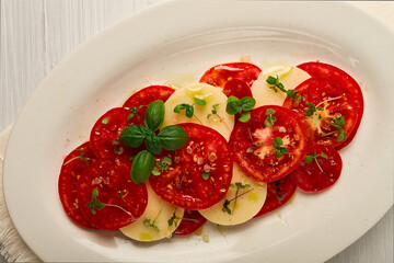 Caprese salad, Italian traditional dish, tomatoes with mozzarella cheese, basil and spices, top view, no people,
