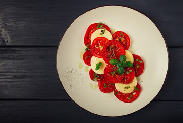 Caprese salad, Italian traditional dish, tomatoes with mozzarella cheese, basil and spices, top view, no people,