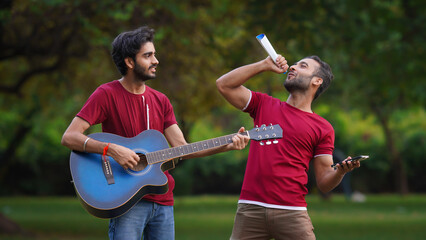 Two Indian boys entertaining people by singing and playing guitar image