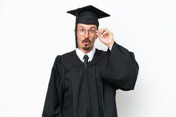 Young university graduate man isolated on white background with glasses and surprised